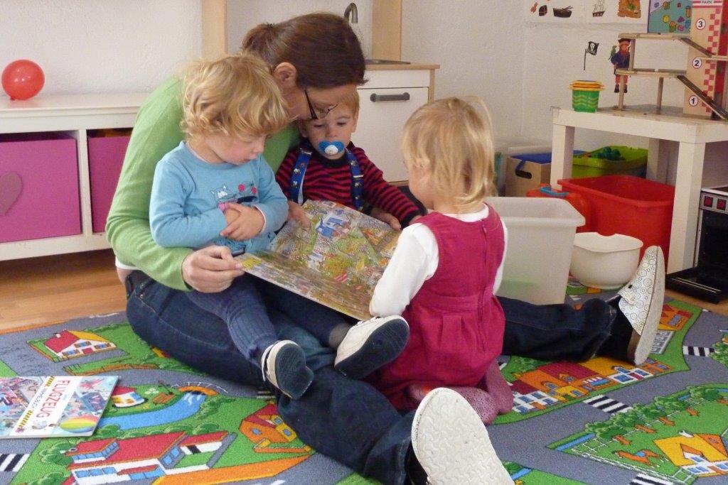Tagesmutter mit 3 Kindern beim Lesen